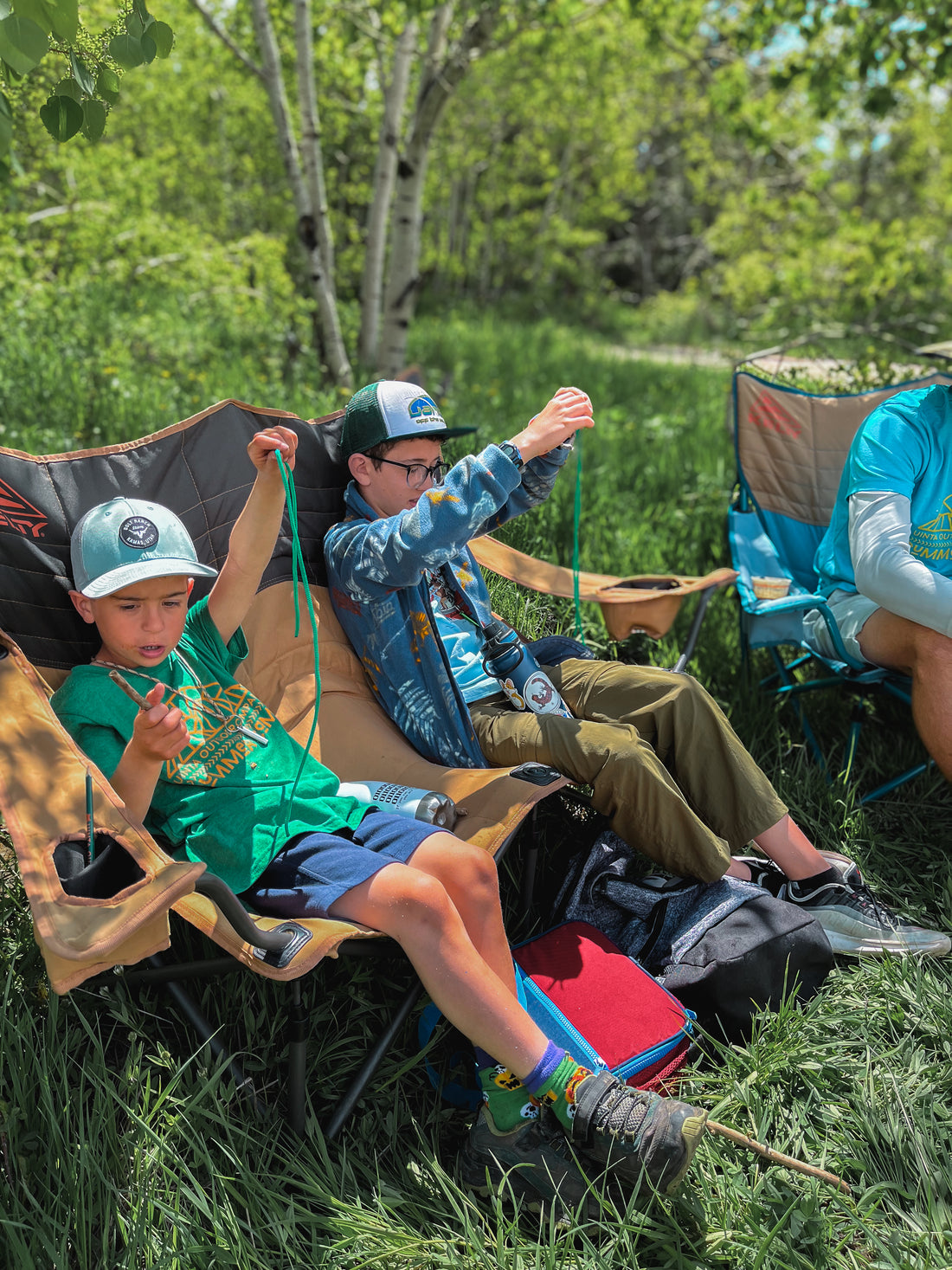Campers sit on camp chairs to practice basic knot tying in the mountains.