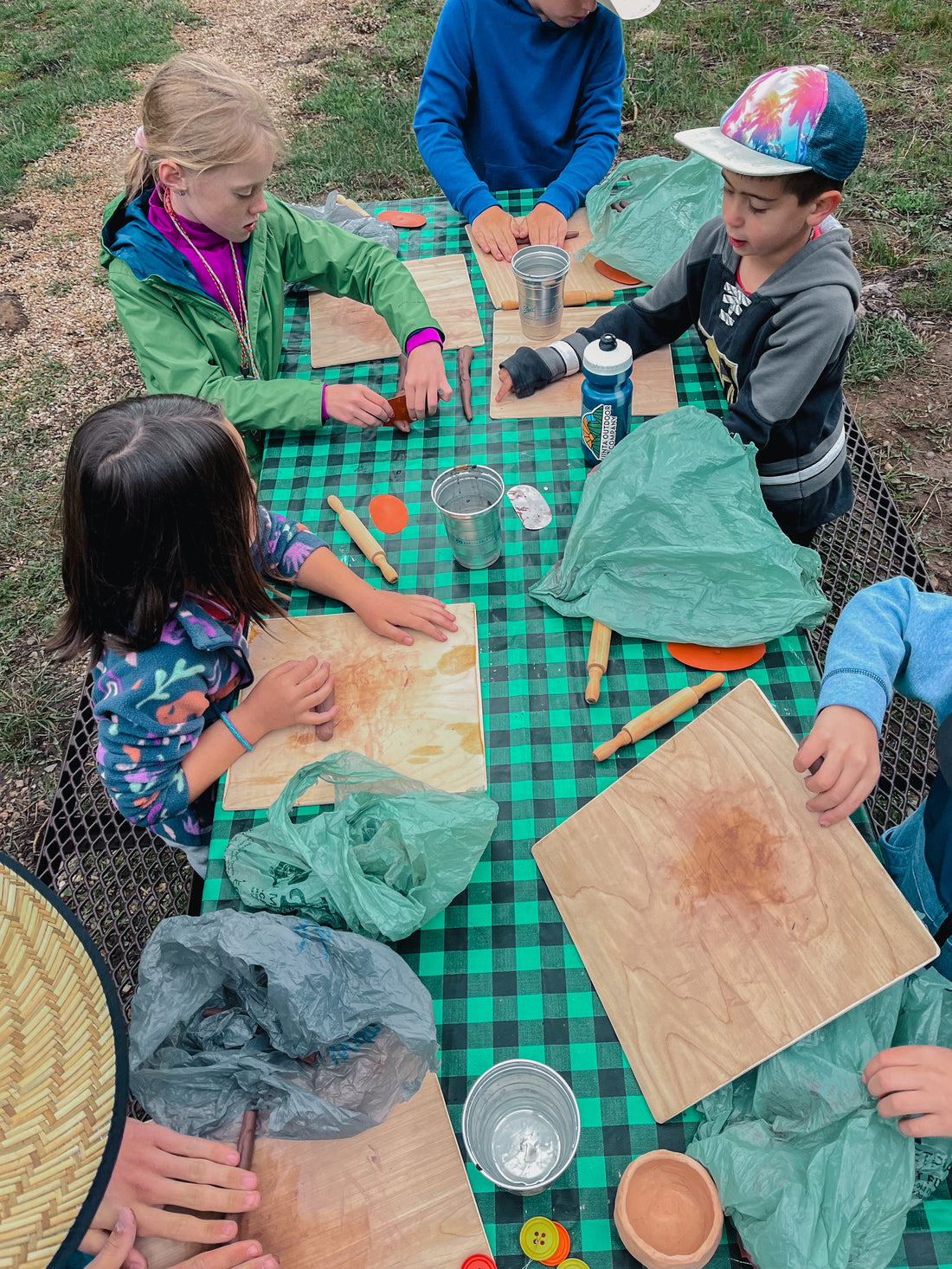 Aerial view of campers working on coil pots at a picnic table in the mountains.