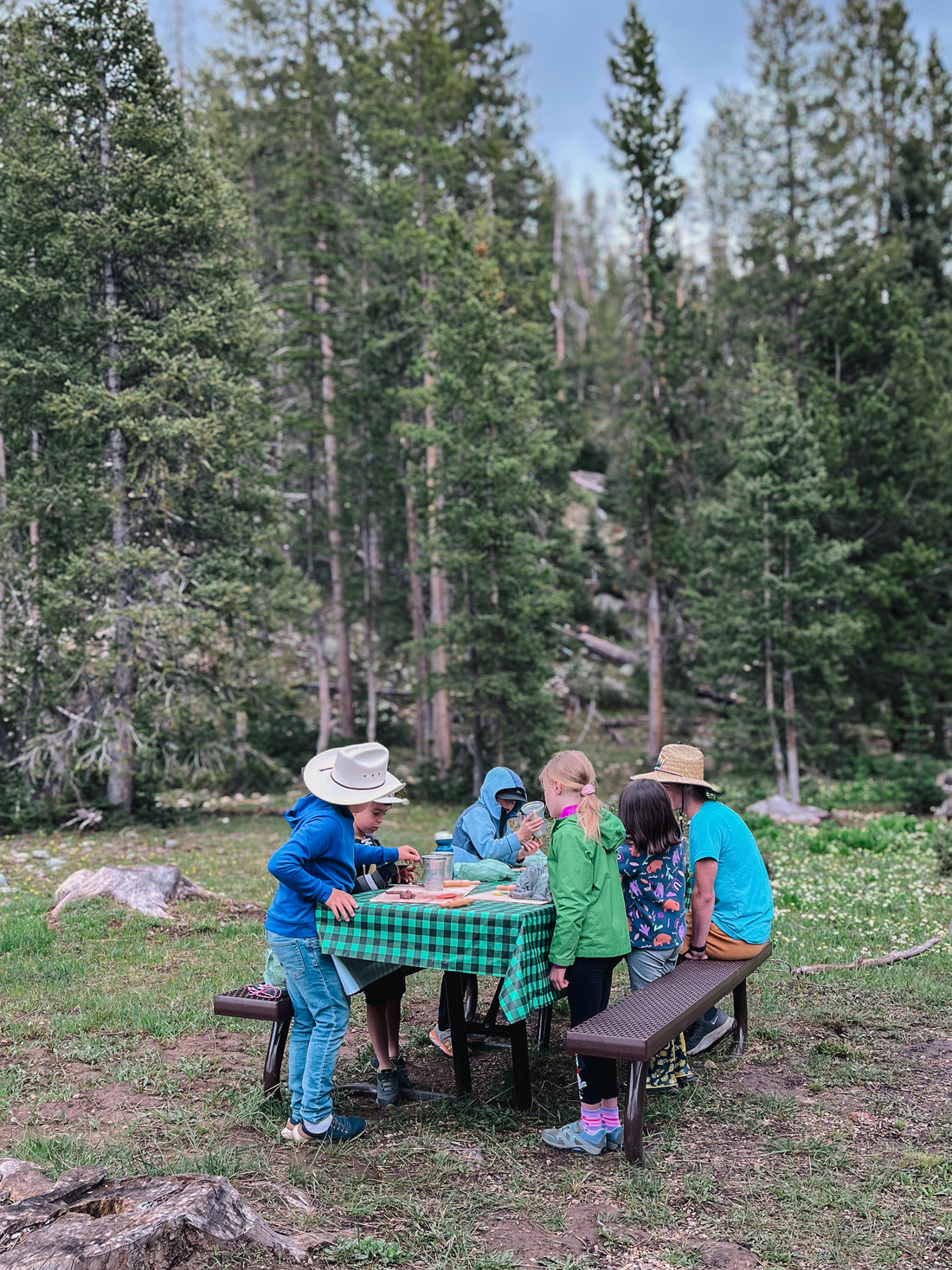 Campers gather at a picnic table for a camp activity in the mountains.