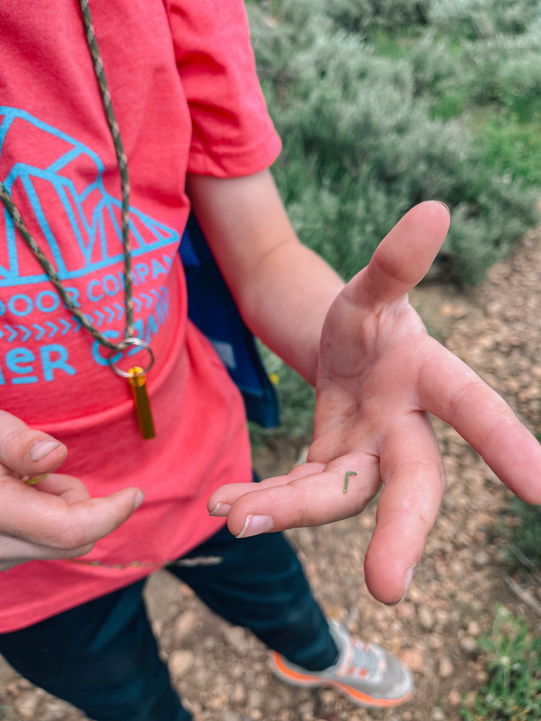 Camper holds a tiny caterpillar on his finger.