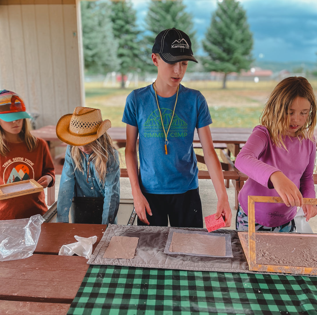 Campers making recycled paper at a park.
