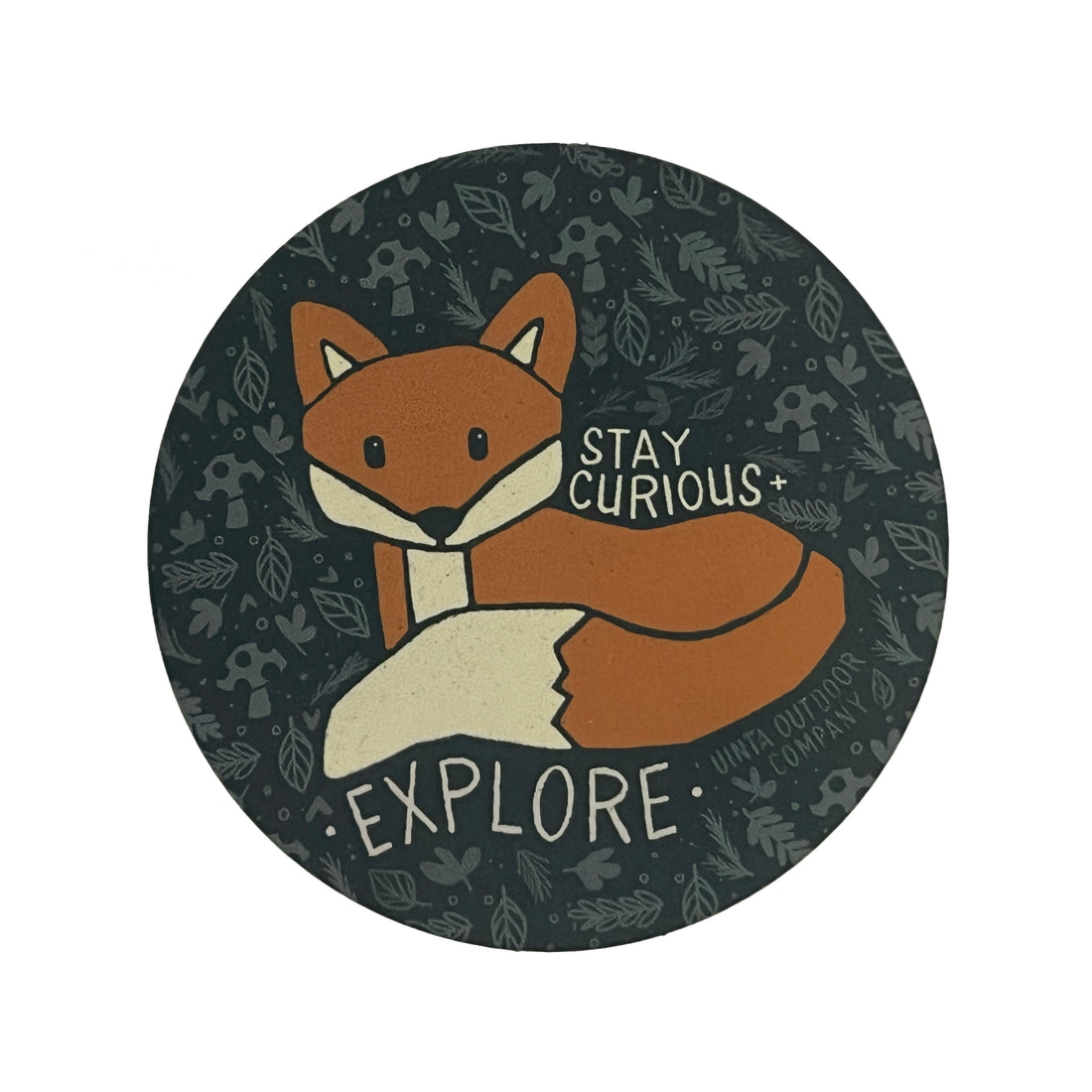 Circle sticker with dark blue background and lighter blue natural elements creating a pattern. Subject is an orange fox laying down with the words: Stay Curious + Explore in off-white surrounding it.