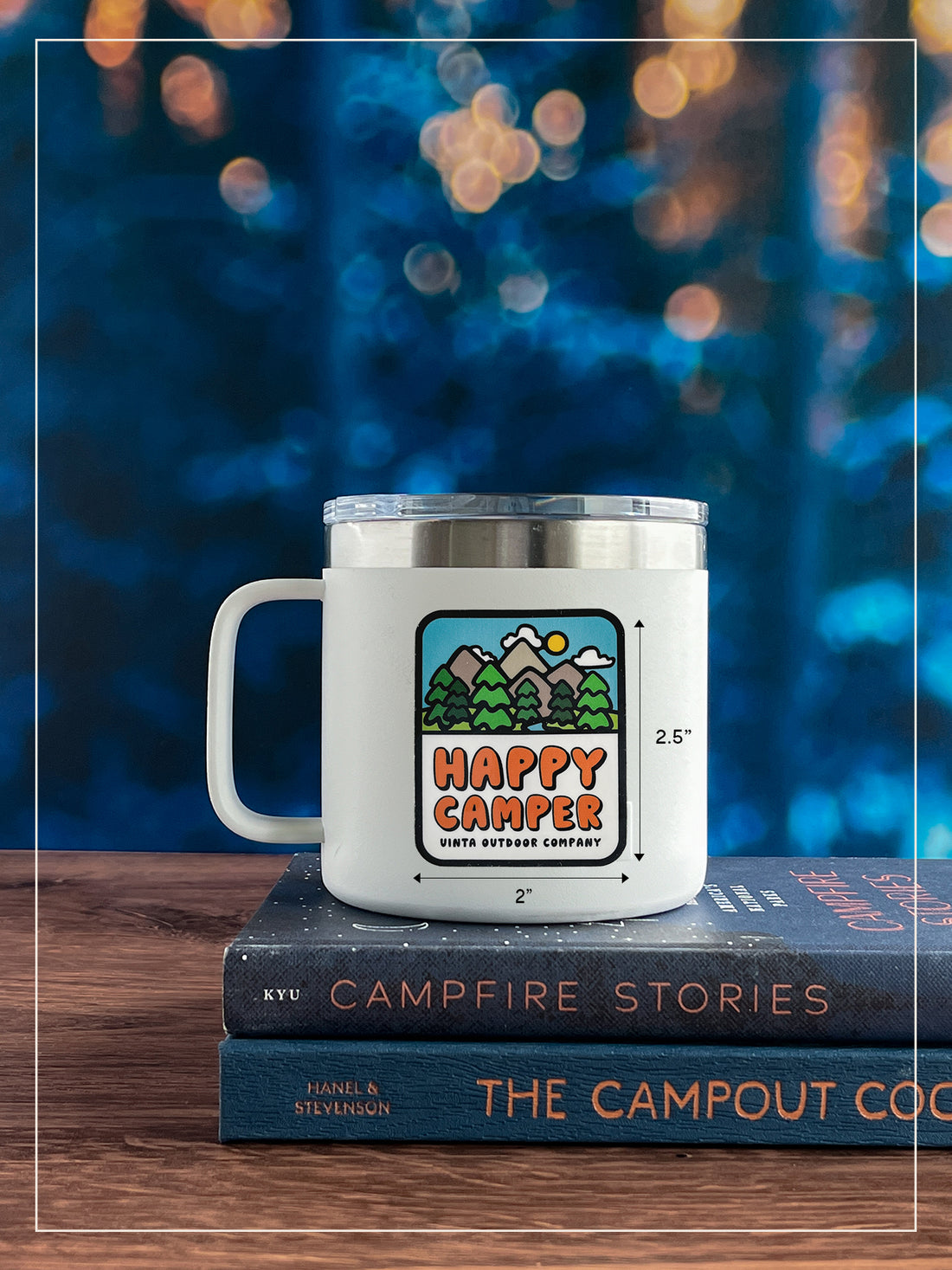 Happy Camper sticker placed on a white mug with trees and lights in the far background.
